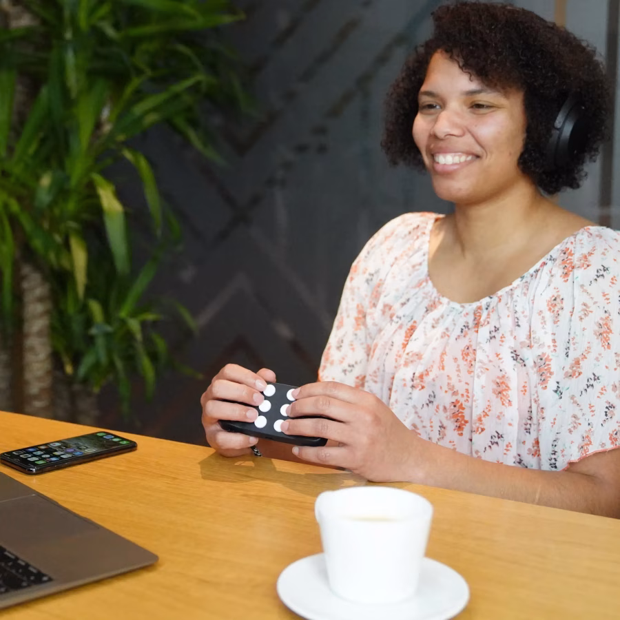 Ver: Mujer sentada utilizando el Hable One para escribir un correo electrónico desde su teléfono móvil